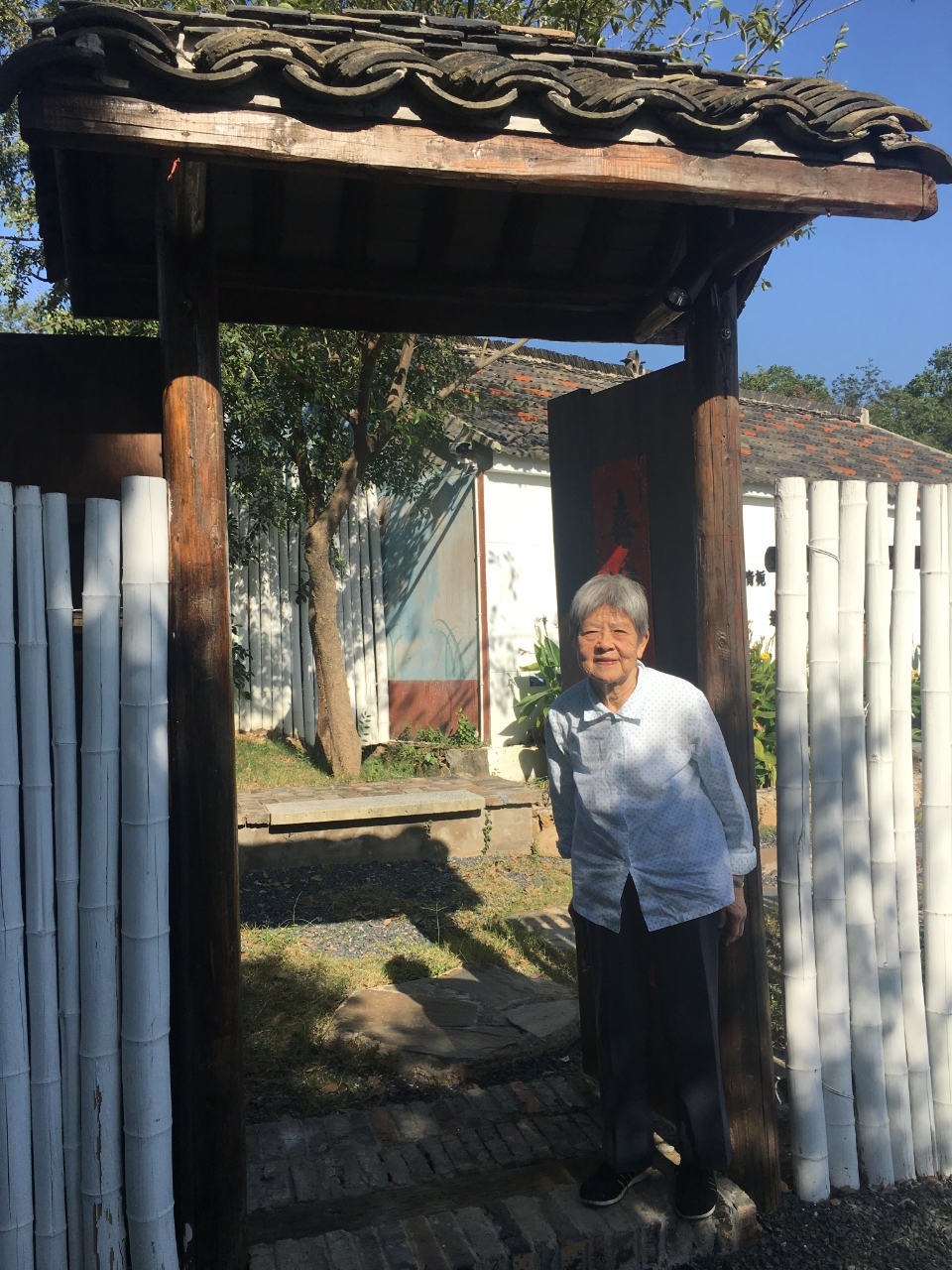 My grandmother standing beneath a traditional gate